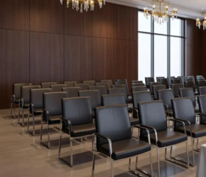 Elegáns konferenciaterem sorban elhelyezett székekkel, modern színpaddal és hangulatvilágítással